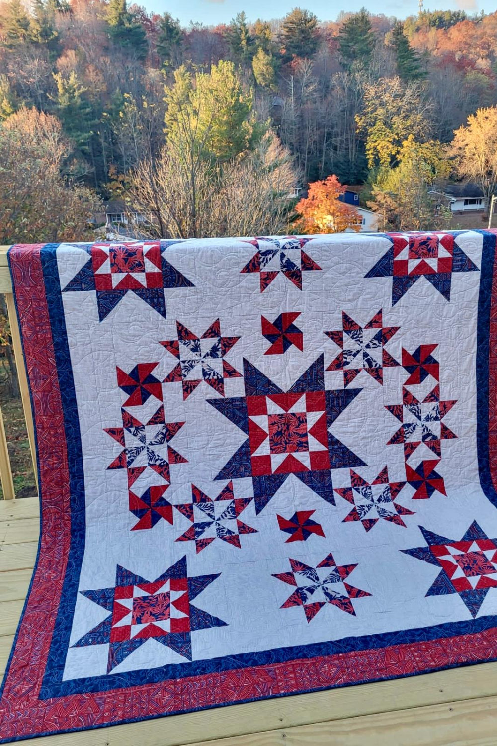 Handmade twin full star quilt draped over railing with autumn landscape backdrop