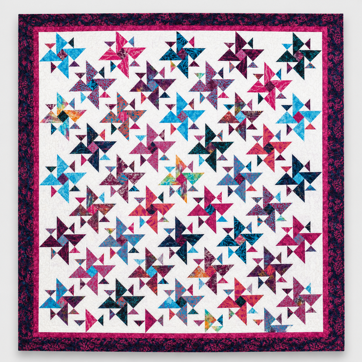 Triangles Galore quilt pattern by Studio 180 Design — vibrant scrappy spinning triangles in jewel tones on a white background with a deep plum border