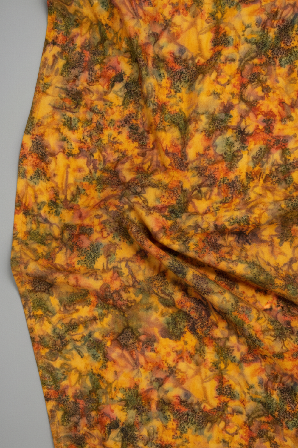 Expressions Batiks Hand-Dyed Orange Multi I quilting cotton fabric by Riley Blake Designs – Pinterest drape shot, soft gathered folds filling frame showing full surface texture of complex multicolor hand-dyed batik with golden amber-orange, olive green, red-orange, and muted brown-grey palette