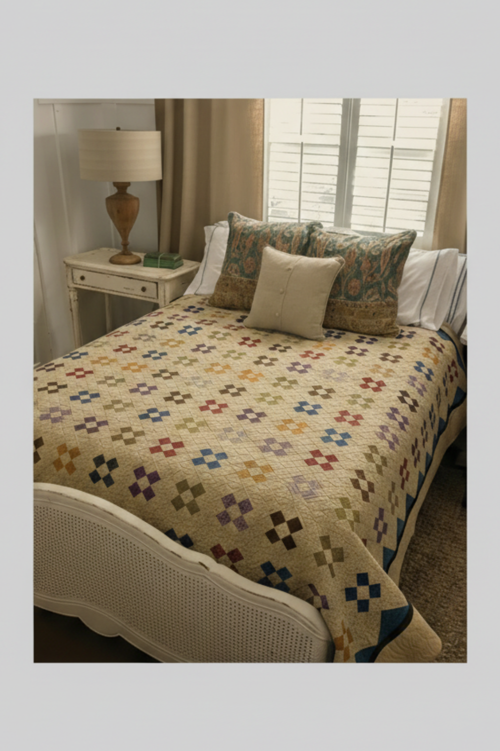 Scrappy patchwork quilt on a bed featuring small repeated blocks in a vintage color palette