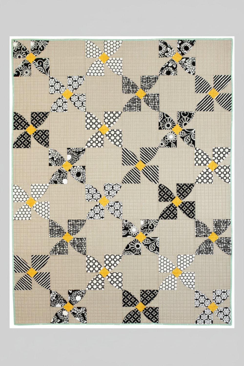 Modern black and white curved quilt with pinwheel-style blocks and yellow accents