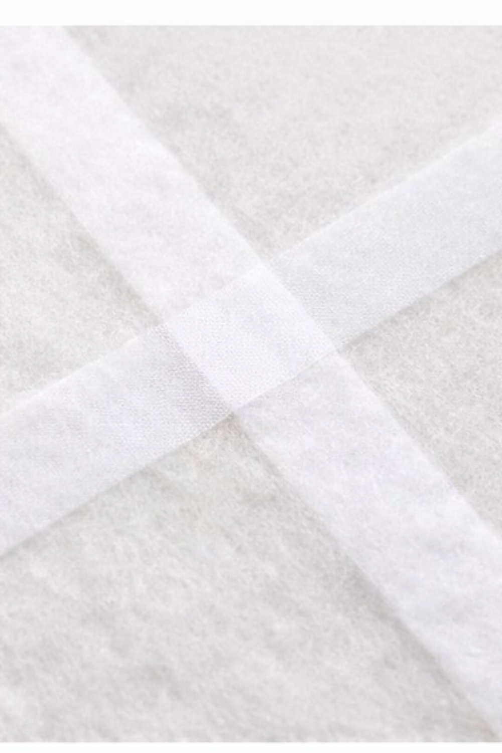 Fusible seam batting tape joining two batting pieces at cross seam detail close-up