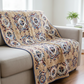 Patterned quilt draped over a beige sofa in a bright living room.