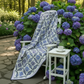 Decorative quilt with blue and white pattern on a bed of purple flowers