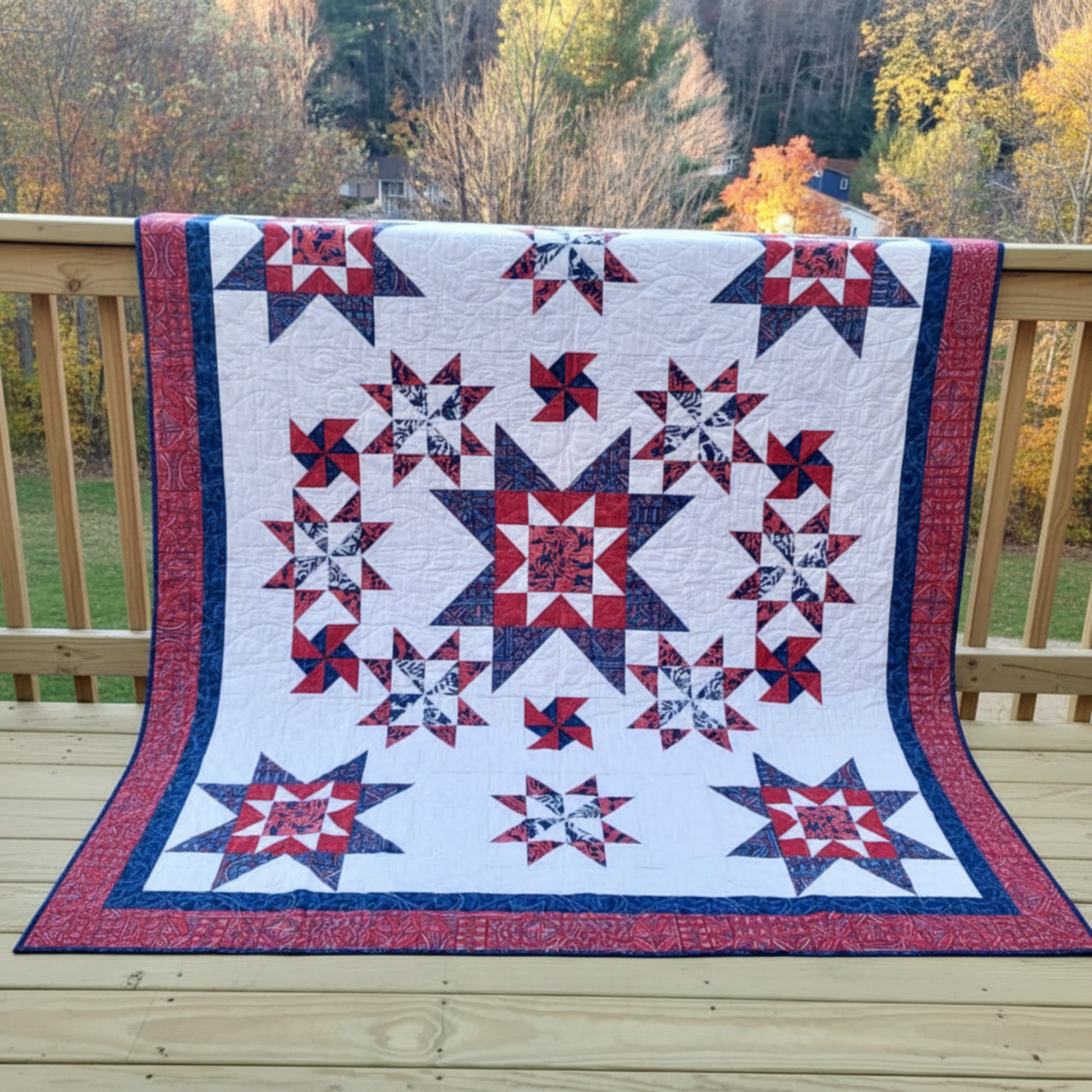 Handmade twin full star quilt draped over railing with autumn landscape backdrop