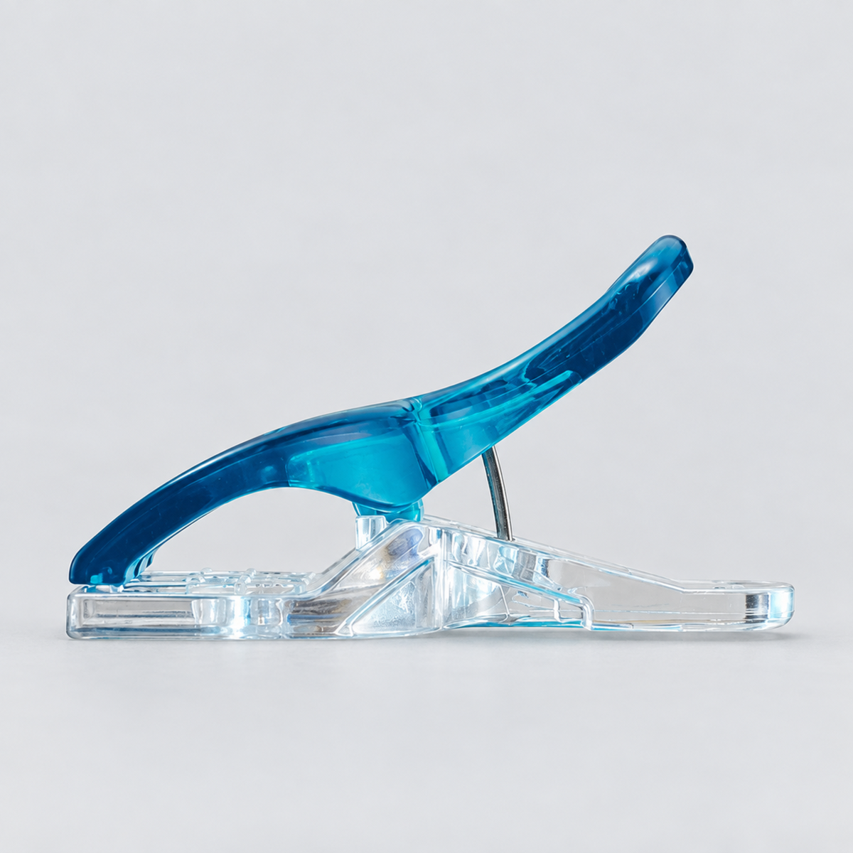 Side profile of a Clover Triple Wide Wonder Clip showing the curved blue handle, flat-back clear base, and metal spring hinge