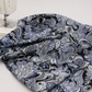 What If Prima Donna Grey/Blue baroque damask quilting fabric draped at sewing machine, showing paisley and floral medallion print in black, periwinkle blue, slate grey, and purple — Paula Nadelstern for Benartex