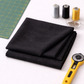 Interwoven Charcoal by Jason Yenter – quilt room lifestyle shot with folded fabric, cutting mat corner, spools of thread, pins, and rotary cutter on light grey base