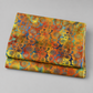 Impressions Gold Daisies quilting cotton fabric folded to show allover large-scale daisy pattern – vibrant golden yellow, orange, and red blooms on teal and blue watercolor ground by Jason Yenter for In The Beginning Fabrics, 100% cotton, 3 yard cut