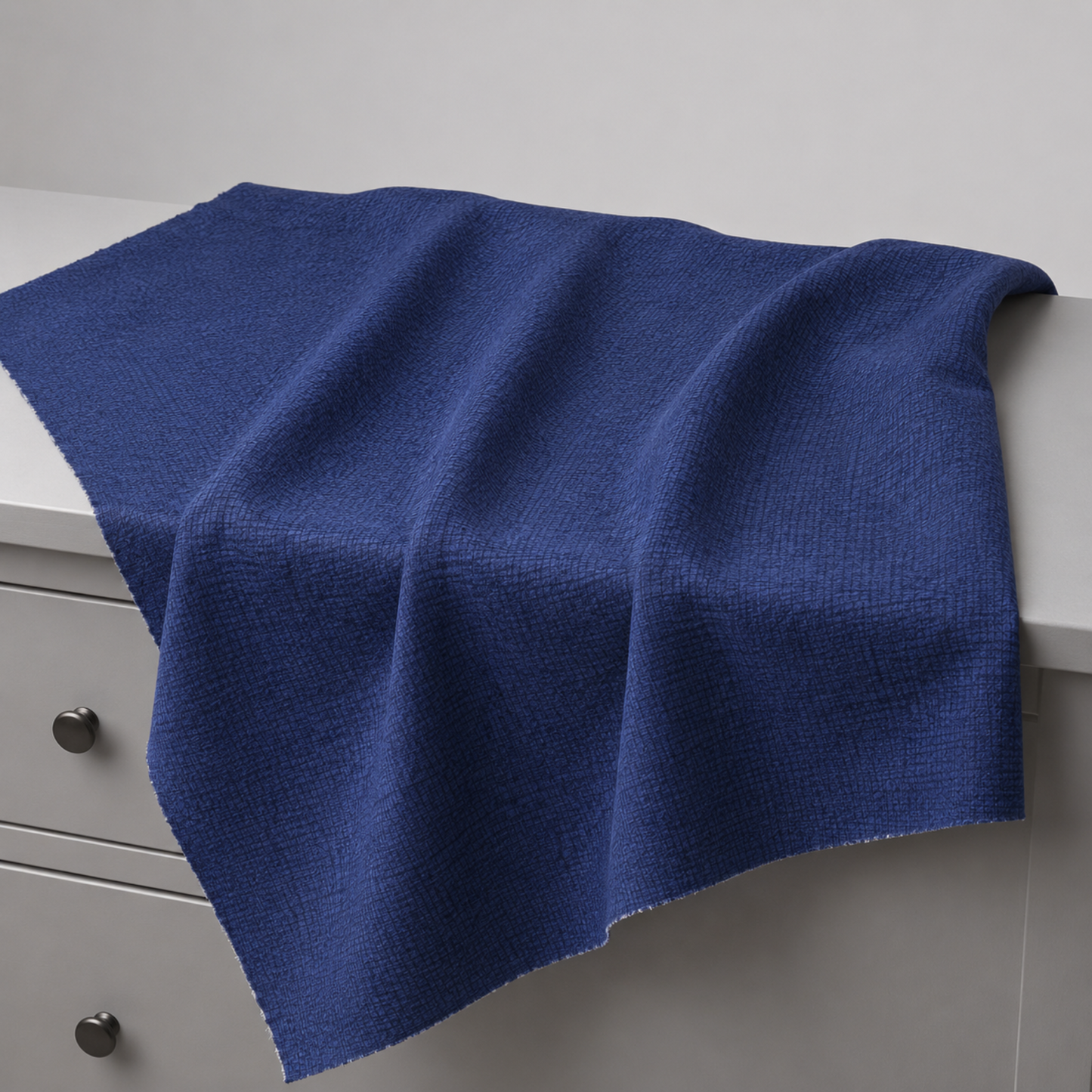 Thatched Navy quilting cotton fabric by Robin Pickens for Moda Fabrics draped over a white dresser with soft natural folds showing the rich deep navy blue tonal crosshatch texture and raw cut edges. Available at IraRobi Quilts.
