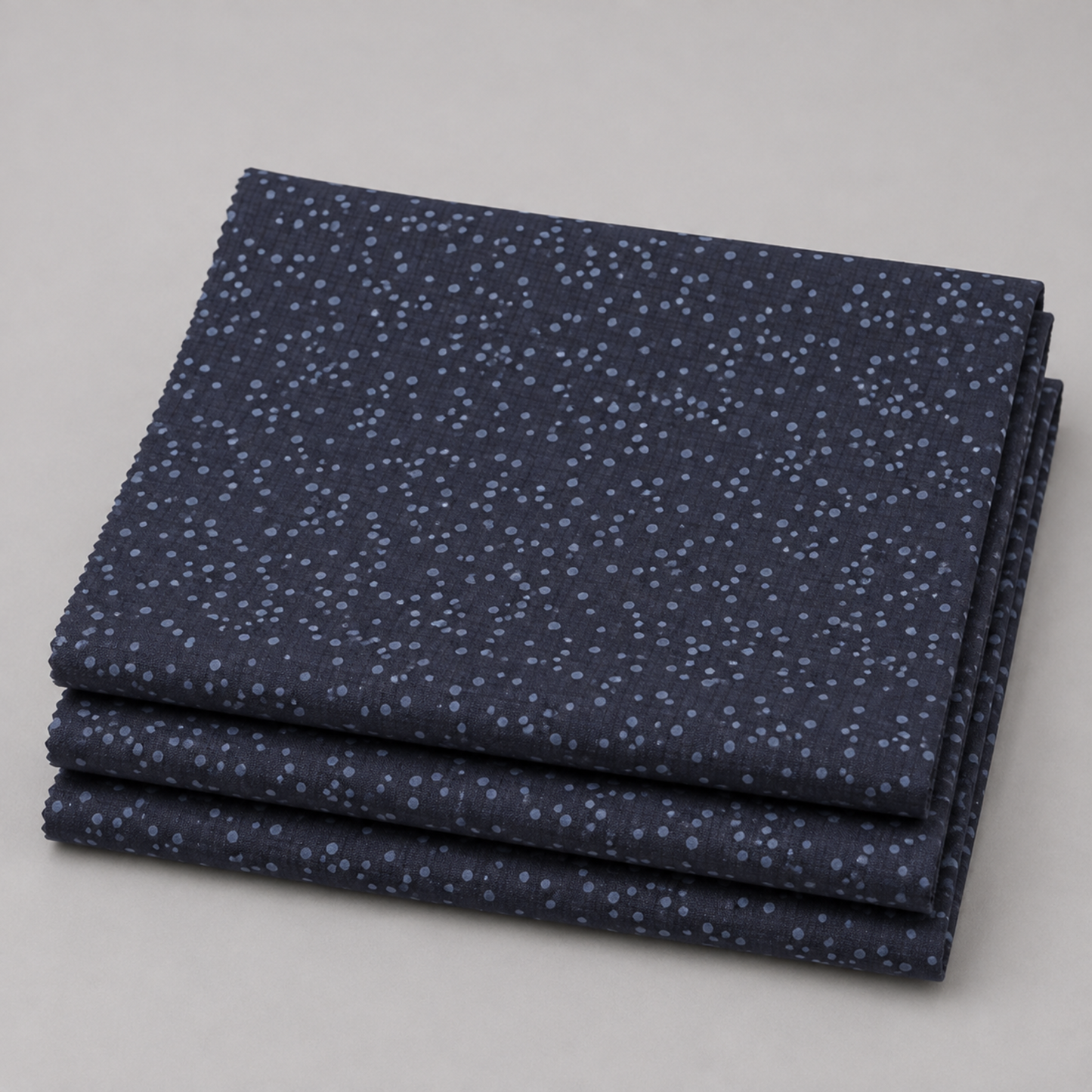Dotty Thatched Indigo quilting cotton fabric by Robin Pickens for Moda Fabrics neatly folded in a stack on a light grey background showing the deep indigo-charcoal ground with scattered tonal grey dots. 100% cotton, 43–44" wide. Available at IraRobi Quilts.