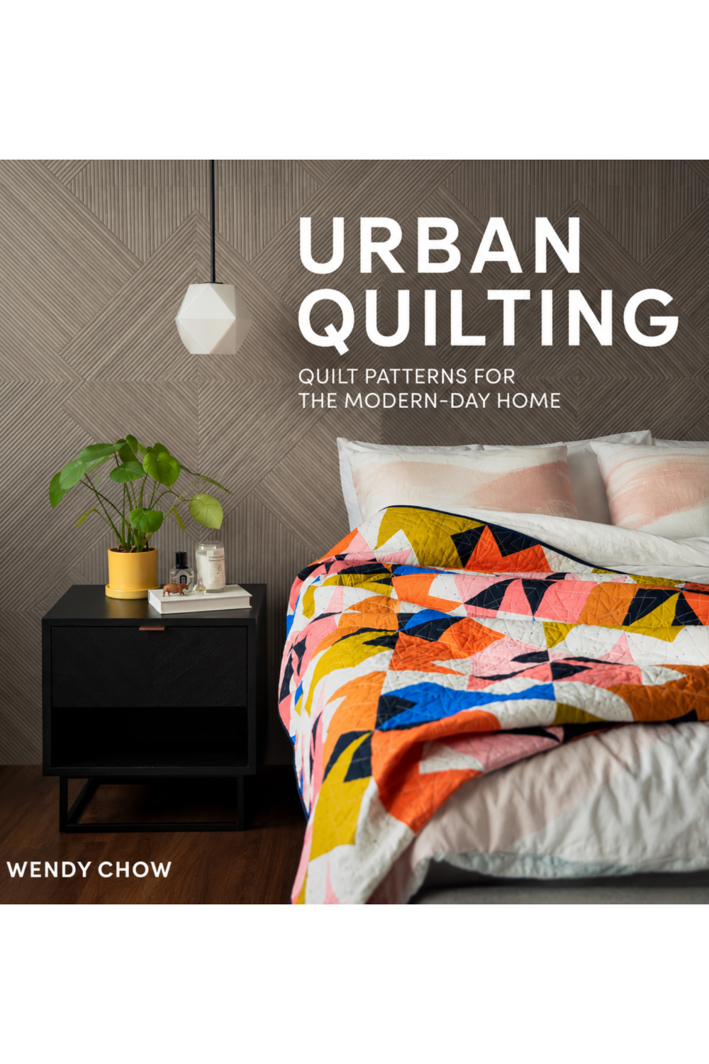 Urban Quilting book by Wendy Chow — bold multicolor geometric pinwheel quilt on bed in modern bedroom with black nightstand and potted plant — Quilt Patterns for the Modern-Day Home by Paige Tate & Co. — modern quilting book with beginner-friendly patterns in 3 sizes