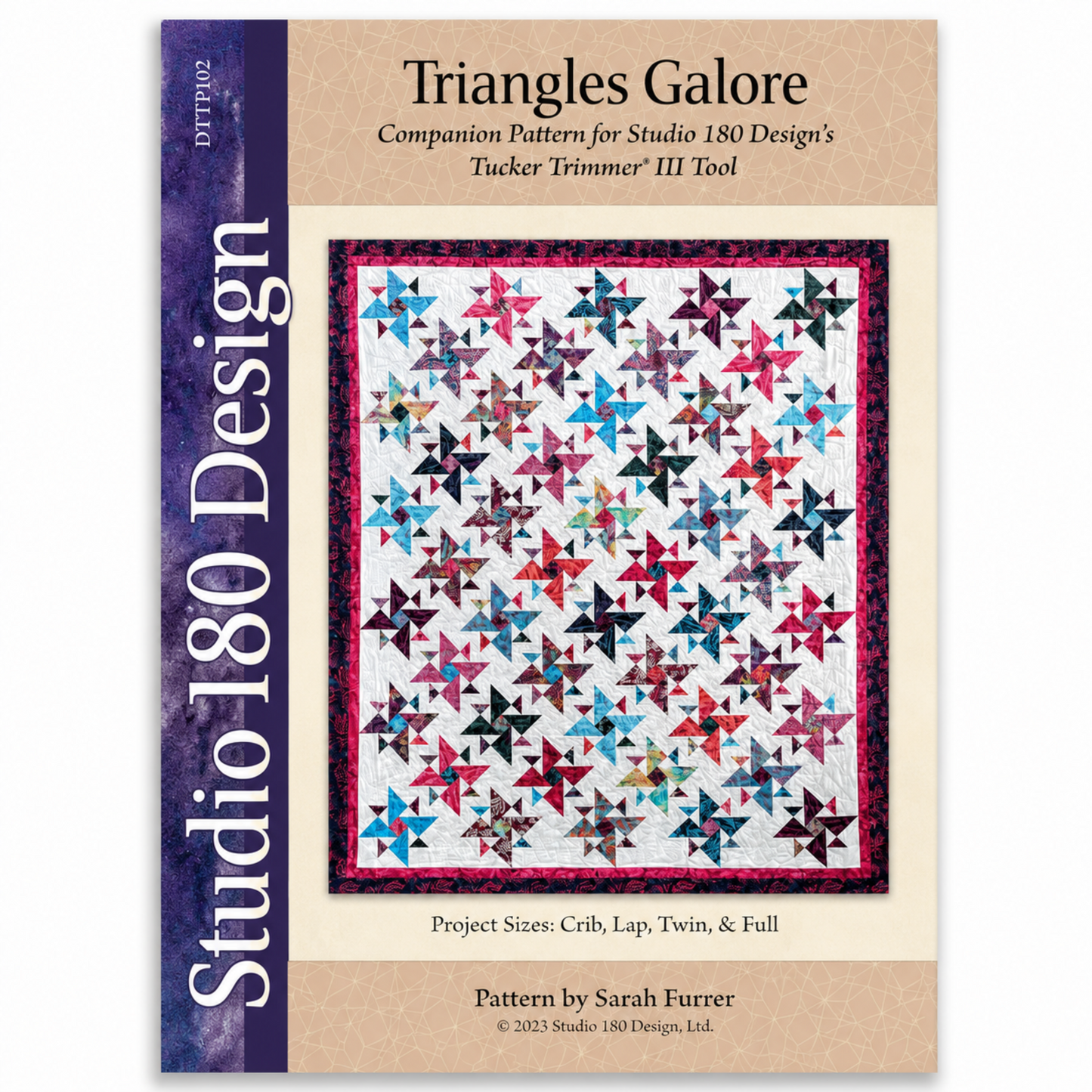 Triangles Galore quilt pattern DTTP102 by Sarah Furrer for Studio 180 Design — scrappy flying geese and triangle blocks in multicolor batiks on white background with raspberry border — available in crib, lap, twin, and full sizes — requires Tucker Trimmer III tool