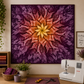 Dream Big Leaf Mulberry Quilt Panel by Jeanie Sumrall-Ajero for Hoffman Fabrics — displayed as a wall quilt in a warm quilting studio — deep purple and burgundy leaf mandala with orange and gold center — Bernina sewing machine, wicker basket with purple fabrics, green plant, mug, scissors, and "Quilting is my Happy Place" sign