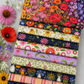 Superbloom quilting fabric collection by Robin Pickens for Moda Fabrics — coordinating prints stacked and fanned with fresh coneflowers, red poppies, and wildflowers — Jewel ombré rainbow floral on top with coordinating Superbloom prints in navy, cream, lavender, and indigo — available at IraRobi Quilts