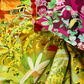 Wild Blossoms Rainbow quilting cotton by Robin Pickens for Moda Fabrics — close-up detail of fabric folds showing bumblebees, orange California poppies, pink clover, magenta wildflowers with bumblebee, chartreuse goldenrod, and white daisies — full rainbow ombré wildflower print detail — available at IraRobi Quilts