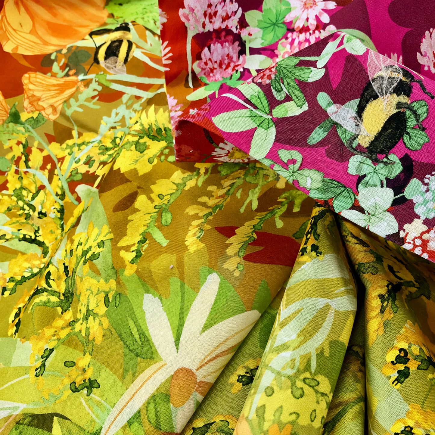 Wild Blossoms Rainbow quilting cotton by Robin Pickens for Moda Fabrics — close-up detail of fabric folds showing bumblebees, orange California poppies, pink clover, magenta wildflowers with bumblebee, chartreuse goldenrod, and white daisies — full rainbow ombré wildflower print detail — available at IraRobi Quilts