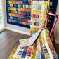 Bar Hop quilt pattern by Robin Pickens made with Wild Blossoms Rainbow fabric by Robin Pickens for Moda Fabrics — two Bar Hop quilts displayed: large rainbow strip quilt on navy blue background wall and smaller version draped on floor showing full rainbow colorway from cobalt blue through purple, red, orange, yellow-green wildflower prints with cream sashing — Bar Hop pattern available at IraRobi Quilts