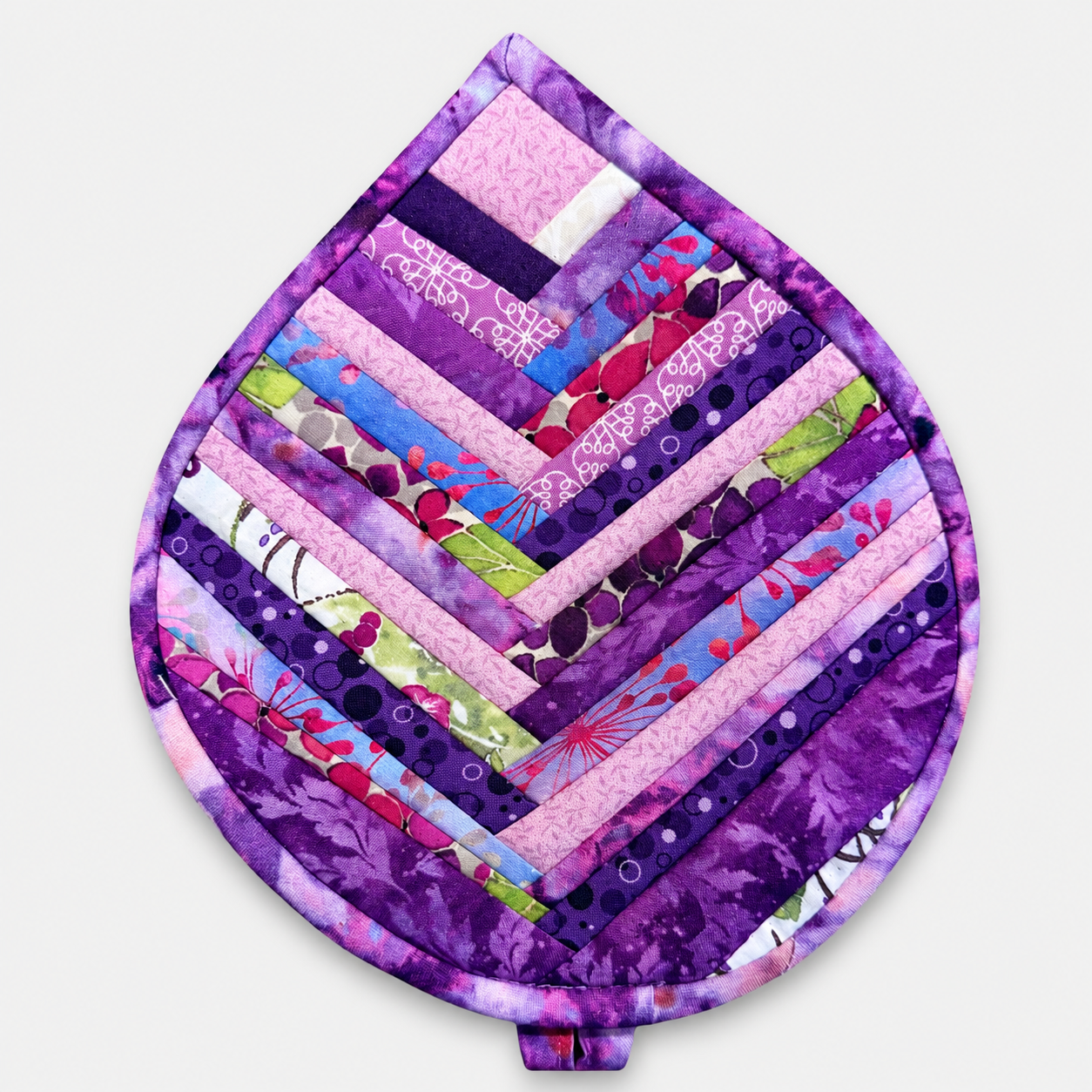 Leaf-Shaped Quilted Hot Pad – Violet Jewel, front view showing herringbone chevron strip piecing in rich jewel-tone purples with purple batik border – handmade by IraRobi Quilts