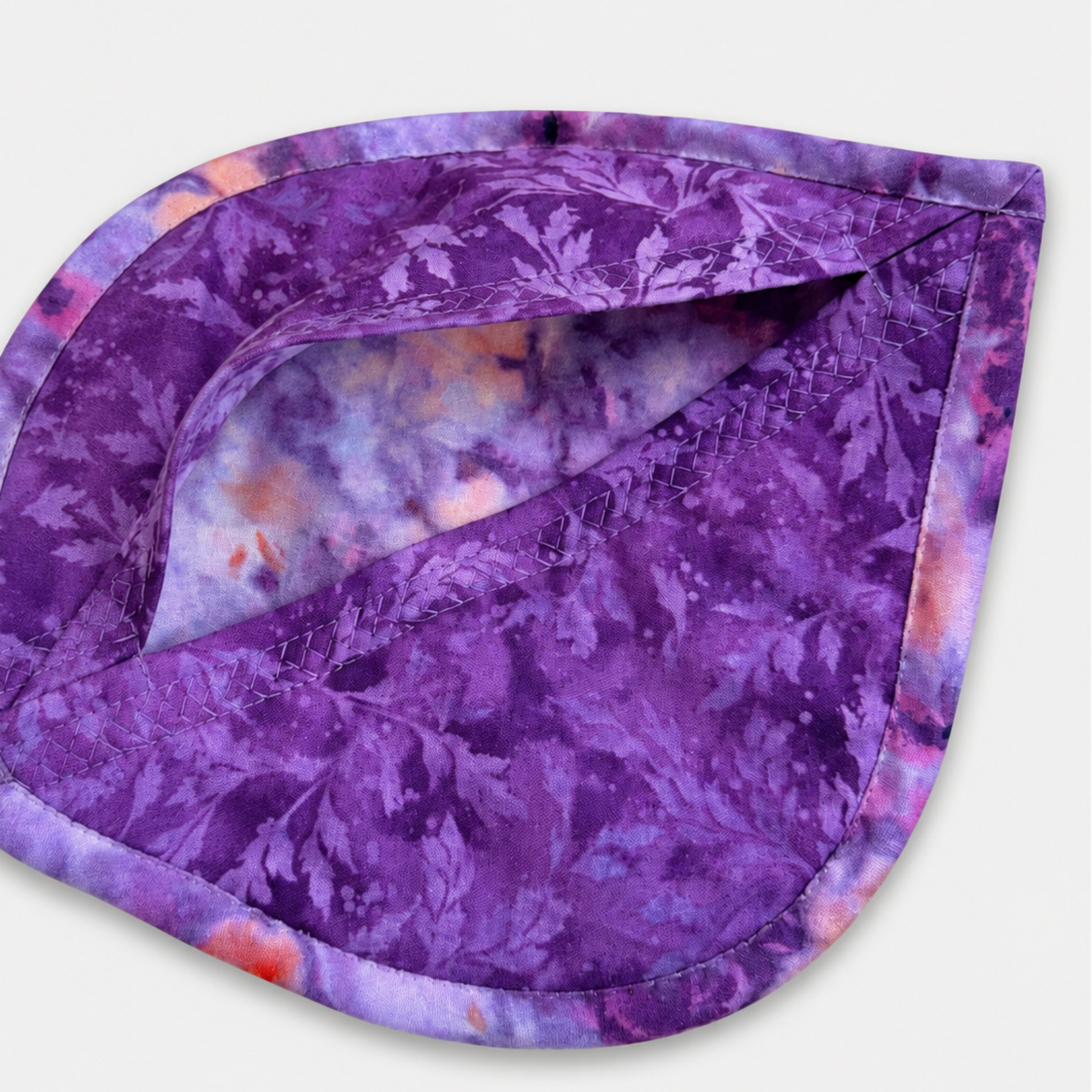 Leaf-Shaped Quilted Hot Pad – Violet Jewel, pocket open showing deep purple botanical batik lining with crosshatch quilting detail and watercolor batik binding – handmade by IraRobi Quilts