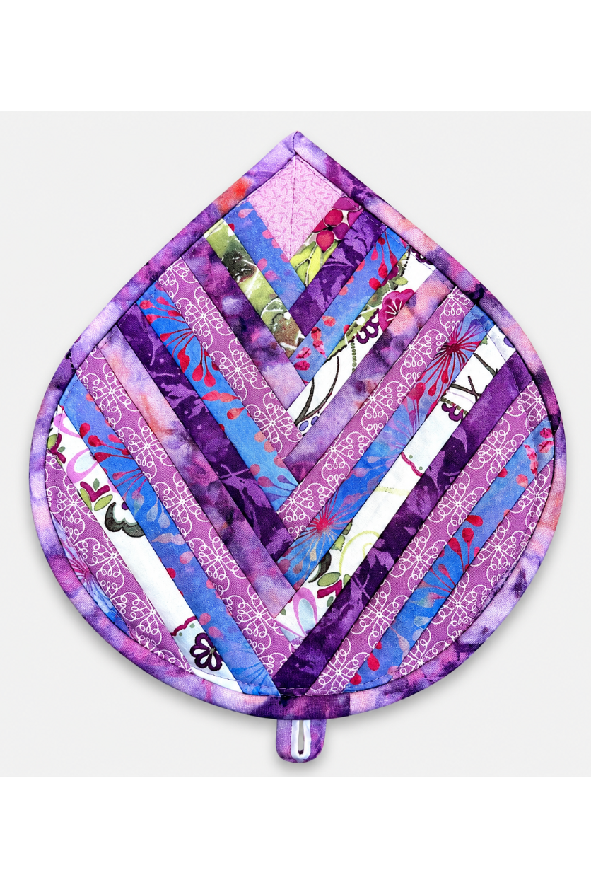 Leaf-Shaped Quilted Hot Pad – Purple Garden, front view showing herringbone chevron strip piecing in purple, lavender, blue, pink, magenta, and floral botanical prints with purple batik border – handmade by IraRobi Quilts
