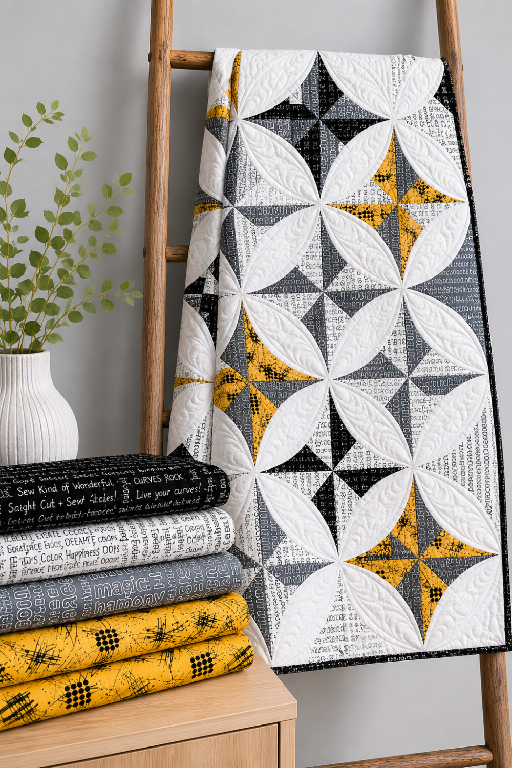 Writing on the Wall Well Worded White quilting cotton by FreeSpirit Fabrics — shown in the Lattice Revival Quilt Pattern by Sew Kind of Wonderful draped on a wooden ladder alongside coordinating Writing on the Wall fabrics in black, grey, and gold. Coordinating fabrics and quilt patterns available at IraRobi Quilts.