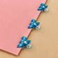Three Clover Triple Wide Wonder Clips clipped along the diagonal edge of a pink nonwoven stabilizer on a wood surface