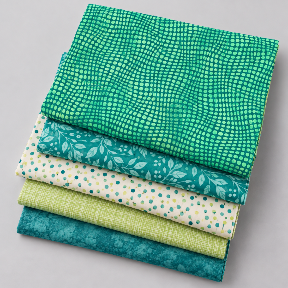 Impressions Mint Dots fabric folded over coordinating teal, cream, and green quilting fabrics