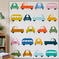 On the Go Automobiles Blue quilting cotton by Jason Yenter for In The Beginning Fabrics — shown as the bus block fabric in a full Cool Cars quilt by Sew Kind of Wonderful, displayed on a wall in a bright children's sewing room with colorful car blocks in green, orange, blue, pink, yellow, teal, and red on a white ground. Quilts shown for inspiration feature the Cool Cars Quilt Pattern by Sew Kind of Wonderful — available at IraRobi Quilts.