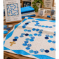 Interwoven Deep Sky Fabric by Jason Yenter for In The Beginning Fabrics used in the border and hexagon bead blocks of a Rosary Baby Quilt on a wooden sewing table — vivid bright sky blue crosshatch tonal coordinating with navy and blue print hexagons forming a rosary chain on a white background, with a gold cross accent. Quilts shown for inspiration feature the Rosary Baby Quilt Pattern by Faith and Fabric, designed by Jen Frost — available at IraRobi Quilts.