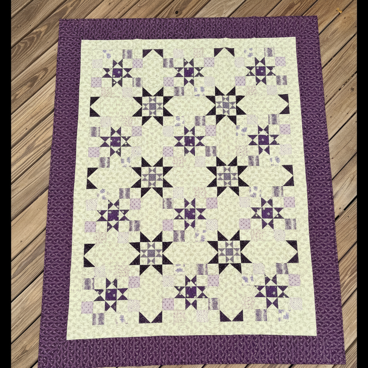 Handmade I Love Purple quilt with star blocks laid flat outdoors