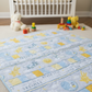 Pastel blue and yellow baby quilt with star and moon motifs laid out in a nursery with a white crib and toys.