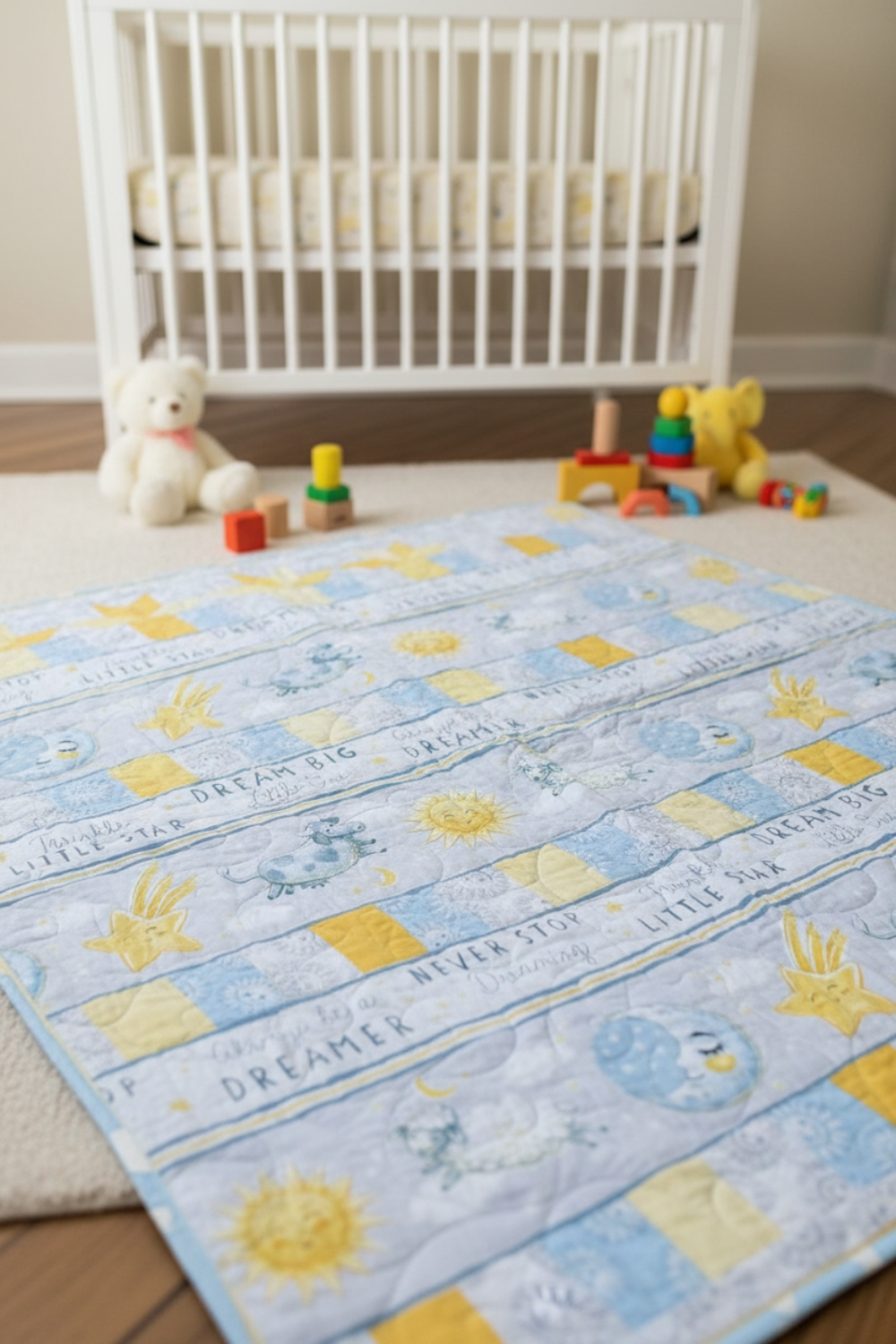 Pastel blue and yellow baby quilt with star and moon motifs laid out in a nursery with a white crib and toys.