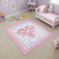 Children's room with a pink and white quilt on the floor, toys scattered around, and a bed in the background.