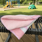 Pink quilt on a bench with a playground in the background