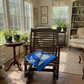Sunroom with wooden rocking chair, table, and armchair with plants and books.