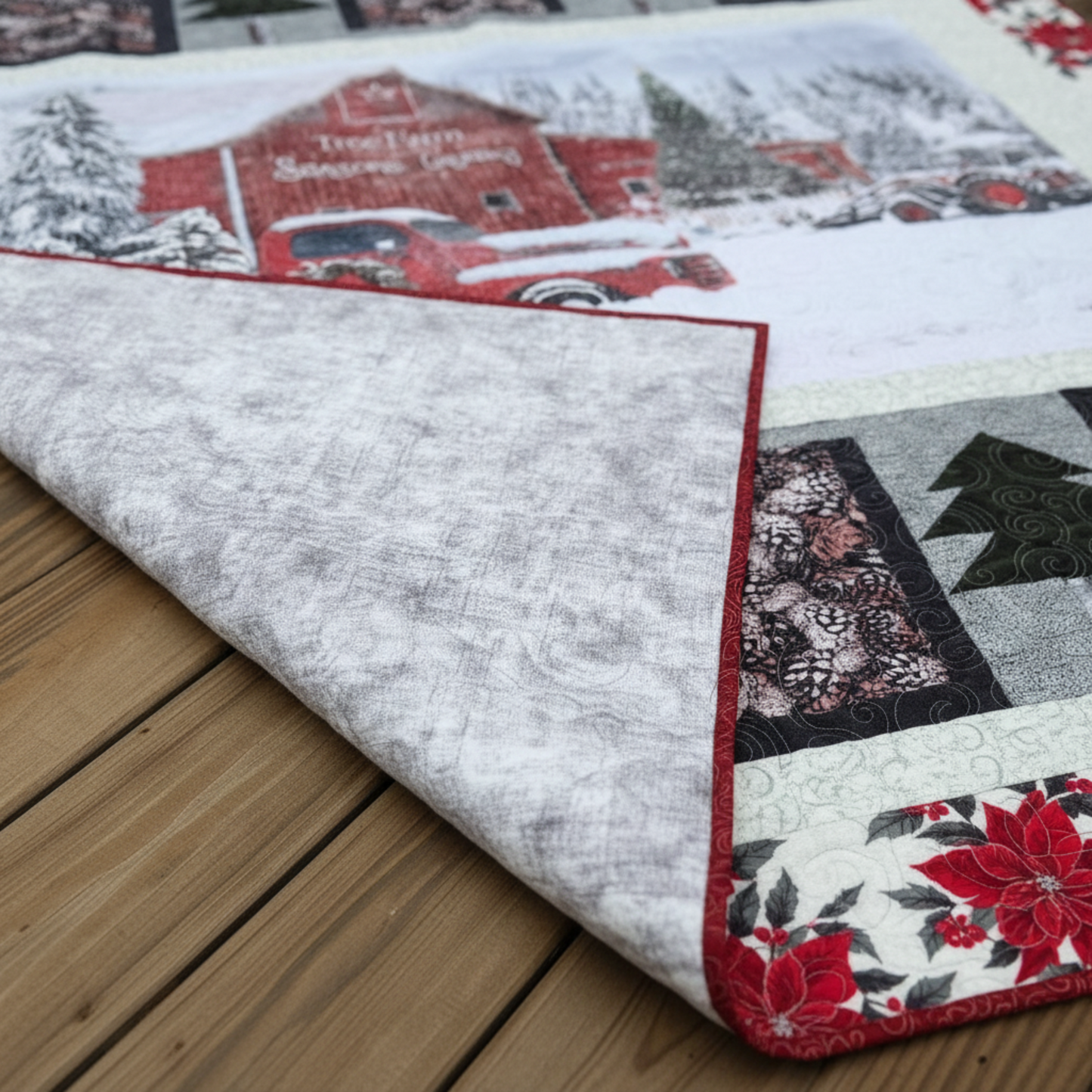 Tree Farm handmade winter quilt showing front snowy barn scene with folded corner revealing soft neutral backing.