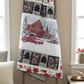 Quilt with a red barn and truck design on a wooden ladder against a beige wall.