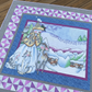 Close-up of the Winter Wonderland quilt showing a whimsical winter illustration with woodland animals, snow-covered hills, and soft blue tones.