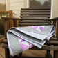 Quilt with pink triangles draped over a wooden chair on a deck.