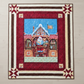 Handmade Christmas quilt featuring Santa in his North Pole workshop, framed by rich red and cream borders with star accents.”