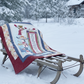 Quilt with a winter scene on a sled in a snowy landscape with a cabin in the background