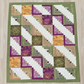 Handmade log cabin quilt with inspirational words like Love, Joy, Peace, Kindness, and Faithfulness in green, purple, gold, and cream tones.