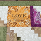 Close-up of handmade log cabin quilt block featuring inspirational word and textured quilting.