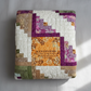 Meaningful handmade log cabin quilt with faith-inspired words in soft green, purple, gold, and cream.