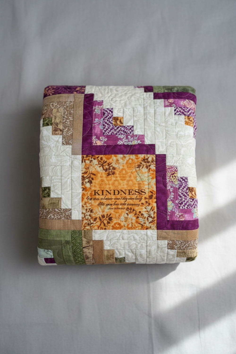 Meaningful handmade log cabin quilt with faith-inspired words in soft green, purple, gold, and cream.
