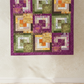 Handmade inspirational quilt with purple borders and colorful patchwork blocks featuring words like Love, Joy, Kindness, Patience, and Faithfulness
