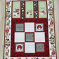 Handmade winter throw quilt with cocoa-themed panels, hot chocolate mugs, marshmallows, and festive red and green borders.
