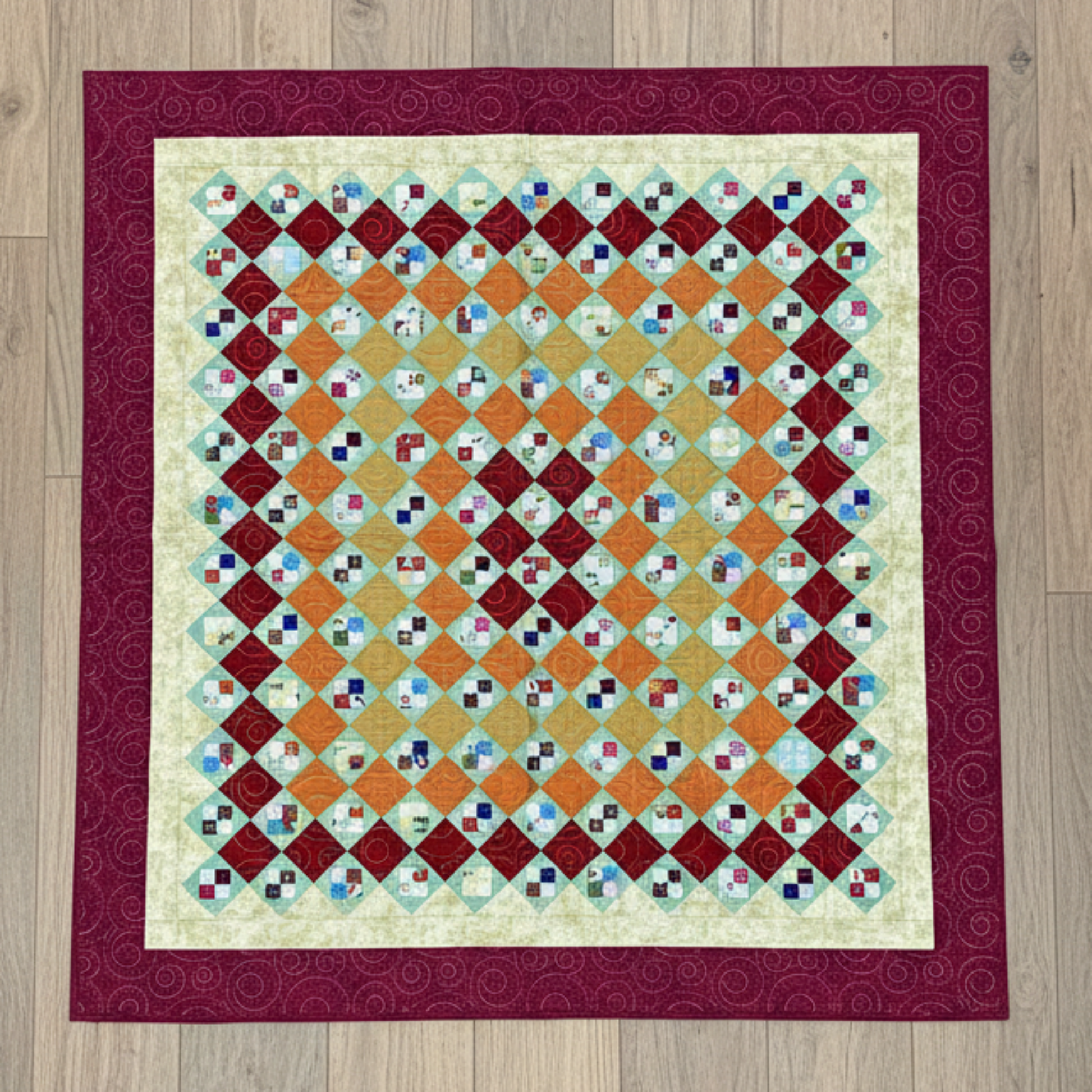 Handmade scrappy 4-patch quilt in brick red, orange, yellow, and green tones, shown flat with a classic patchwork layout