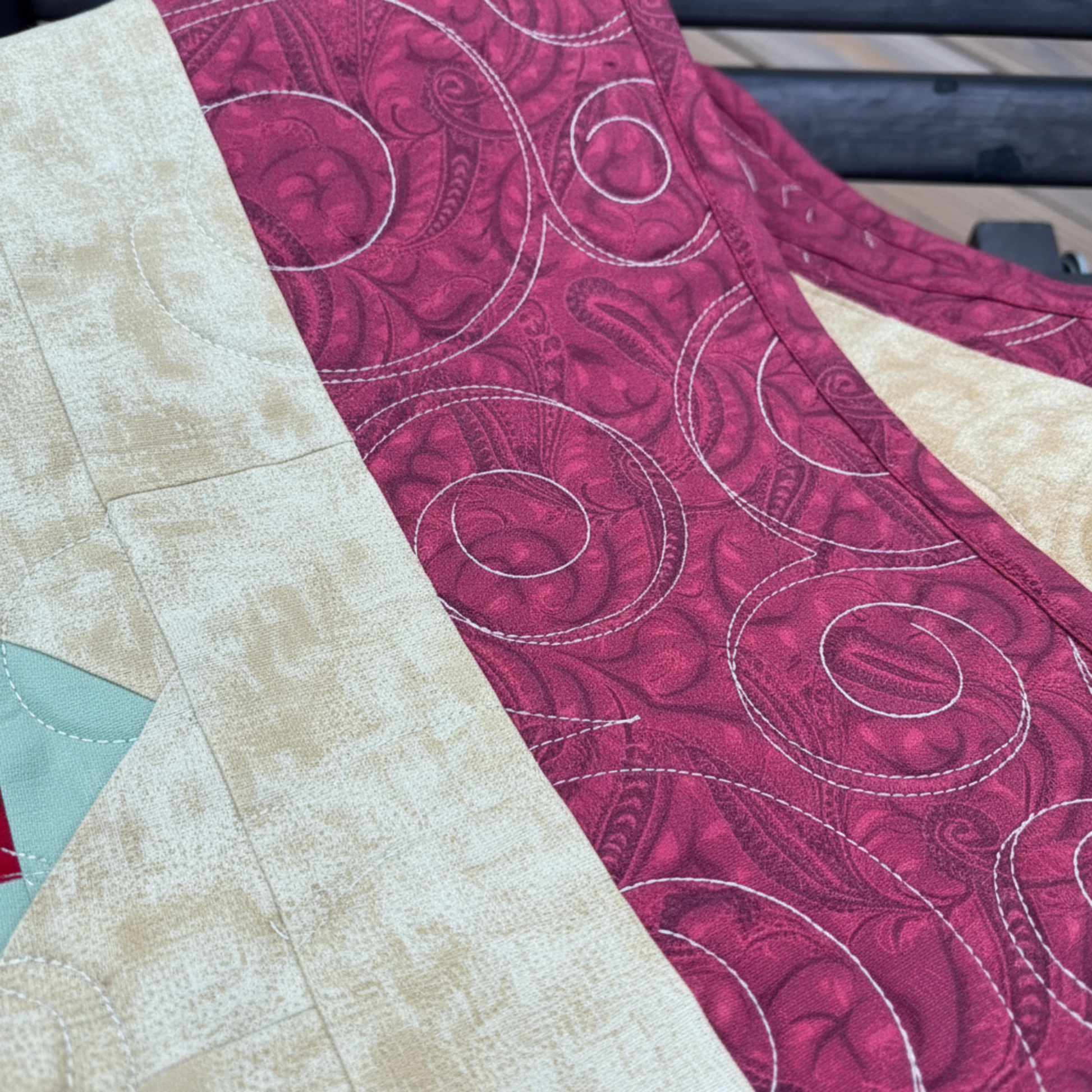 Close-up of scrappy 4-patch quilt blocks highlighting mixed fabrics, swirl quilting, and warm fall colors